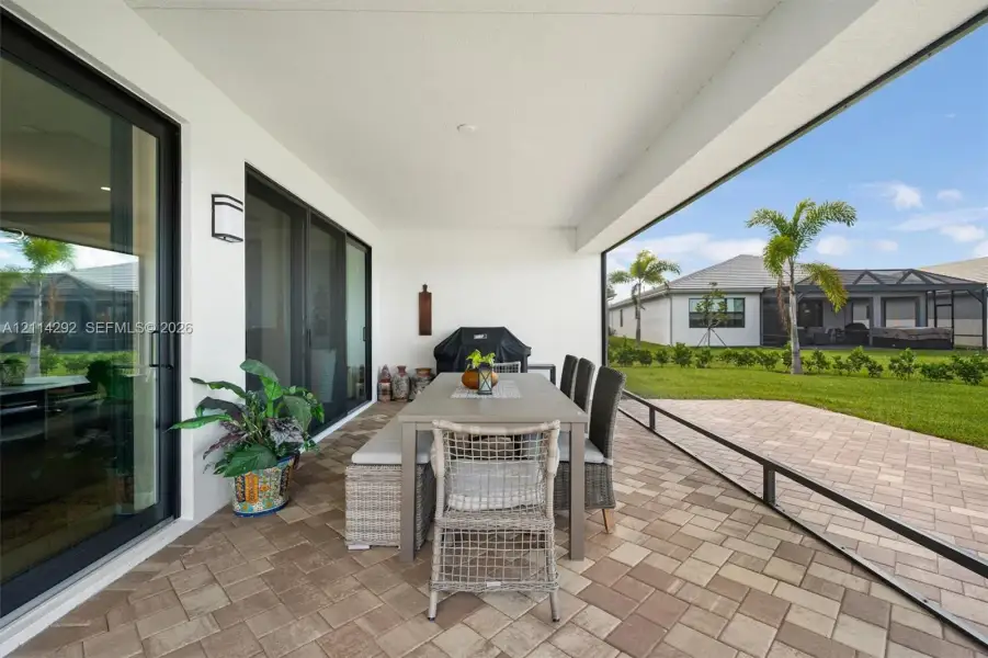 Covered lanai featuring paver flooring, recessed lighting, and multi-panel sliding glass doors opening to a fenced backyard