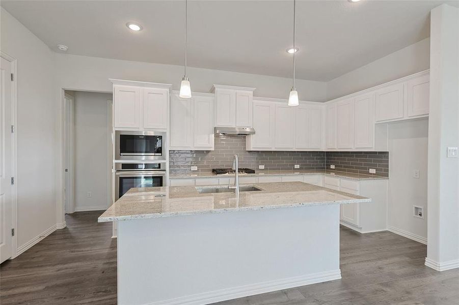 Kitchen with appliances with stainless steel finishes, white cabinetry, wood-type flooring, and ventilation hood