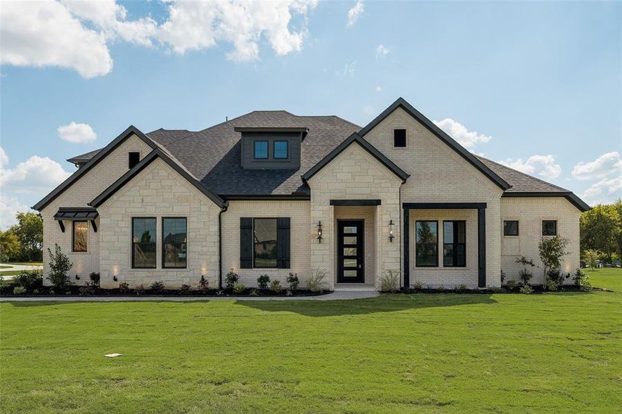 View of front of home featuring stone siding, a front lawn, roof with shingles, and brick siding