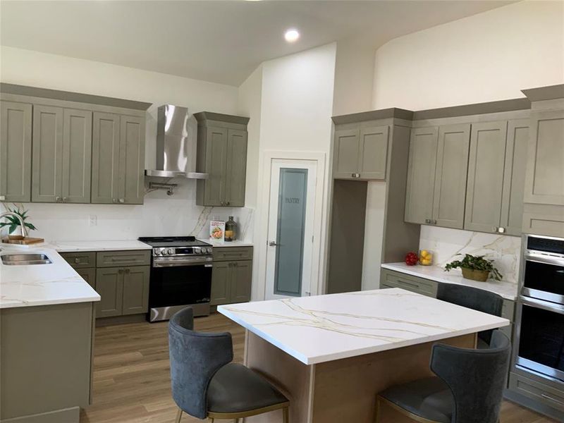 Kitchen with a kitchen breakfast bar, stainless steel appliances, dark wood finished floors, tasteful backsplash, and recessed lighting Kitchen with a kitchen breakfast bar, stainless steel appliances, dark wood finished floors, tasteful backsplash, and recessed lighting