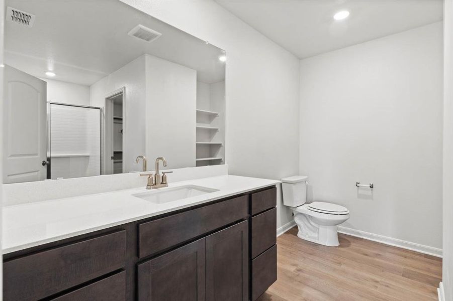 Bathroom featuring wood-type flooring, vanity, toilet, and an enclosed shower