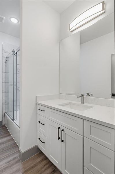 White shaker-style vanity with matte black hardware, integrated sink, and stone-finish countertop