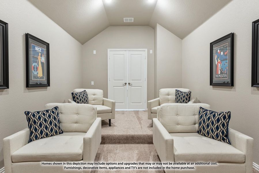 Media room with vaulted ceiling, four white armchairs, carpet flooring, and framed art on walls