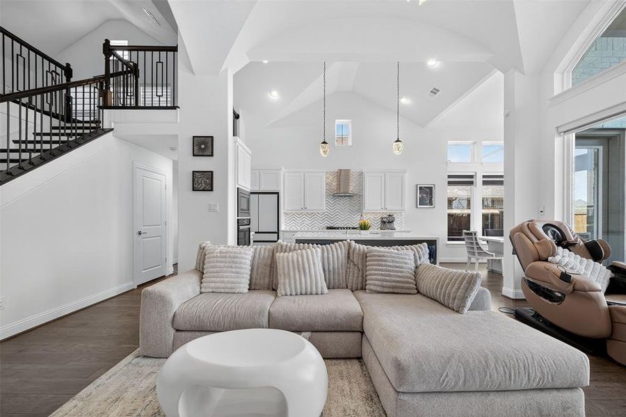 Living room featuring high vaulted ceiling, wood finished floors, stairs, and recessed lighting Living room featuring high vaulted ceiling, wood finished floors, stairs, and recessed lighting
