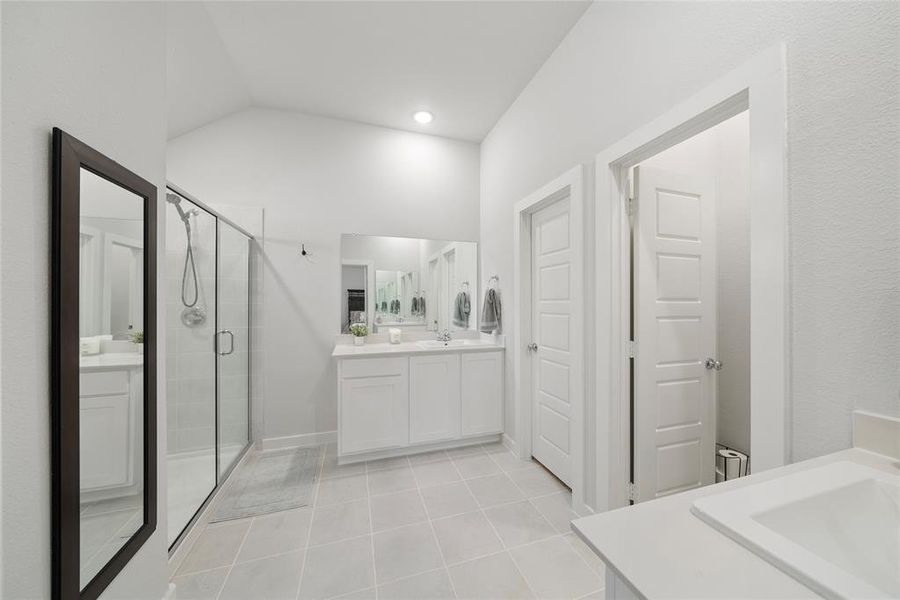 Bathroom with tile patterned floors, vanity, lofted ceiling, and walk in shower