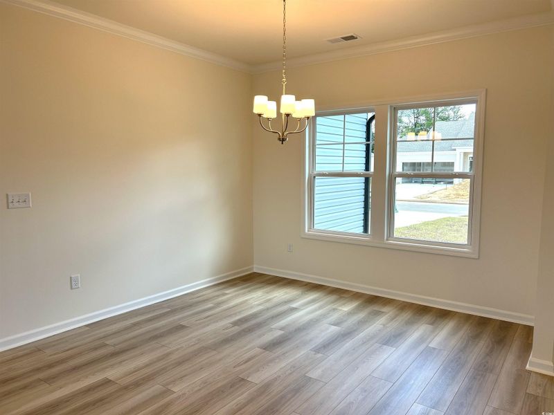 Unfurnished room with a chandelier, light wood-type flooring, and crown molding