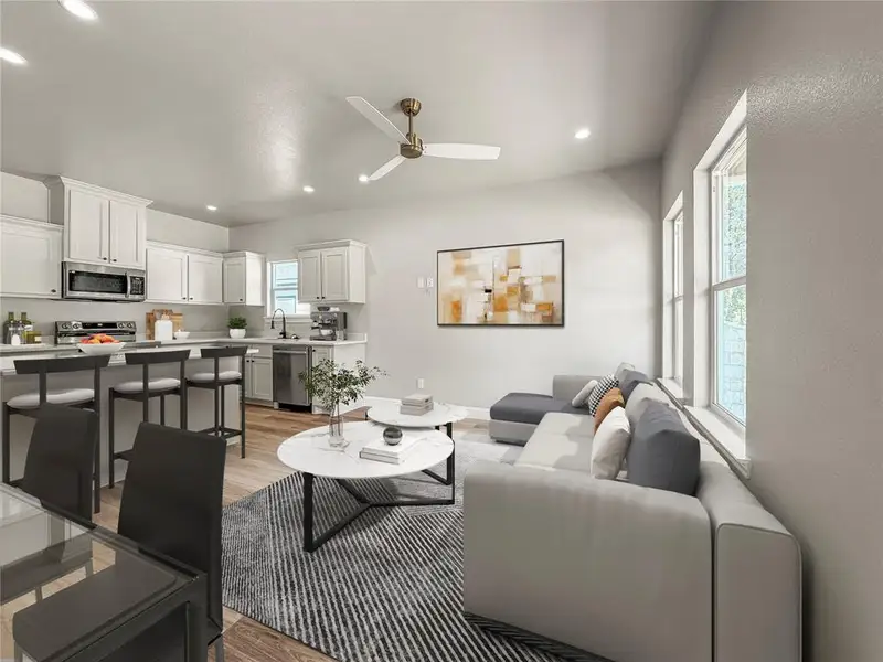 Open-concept living space featuring a kitchen with white cabinetry and stainless steel appliances Open-concept living space featuring a kitchen with white cabinetry and stainless steel appliances