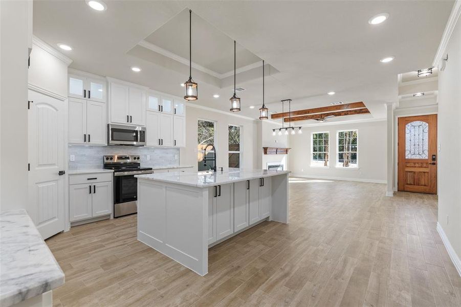 Kitchen featuring white cabinets, plenty of natural light, stainless steel appliances, and decorative light fixtures