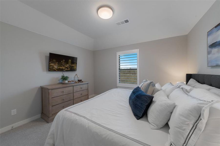 Bedroom featuring visible vents, vaulted ceiling, light carpet, and baseboards