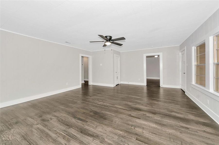 Unfurnished living room featuring dark wood-type flooring and a ceiling fan Unfurnished living room featuring dark wood-type flooring and a ceiling fan