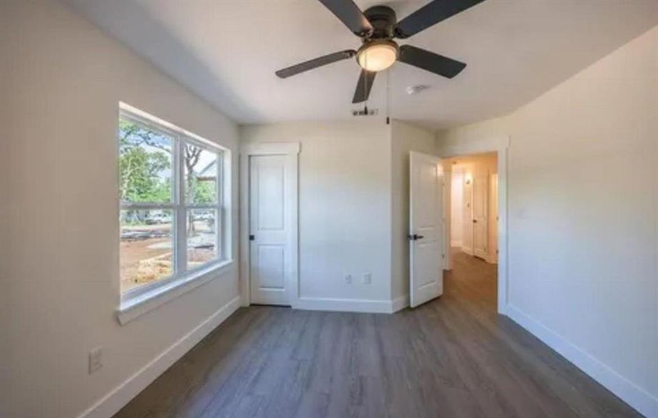 Unfurnished bedroom with dark wood-style flooring, a ceiling fan, and a closet