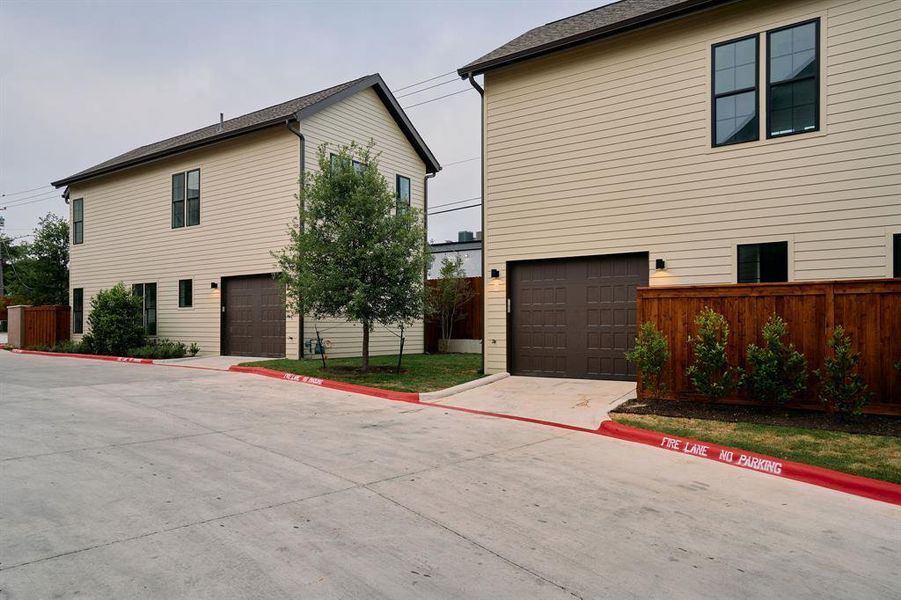 Contemporary two-story exterior with light beige siding, dark-framed windows, and a brown garage door