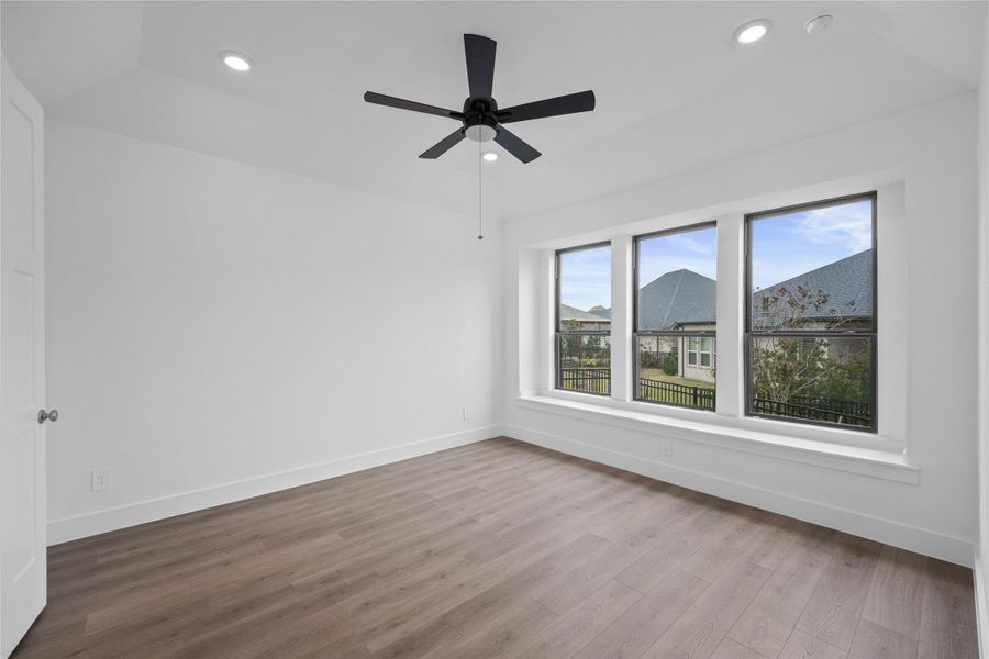 Relax and unwind after a long day in this impressive primary suite! This generously sized room offers laminate flooring, neutral-toned paint, high ceilings with a ceiling fan, and large windows for added comfort and tranquility.