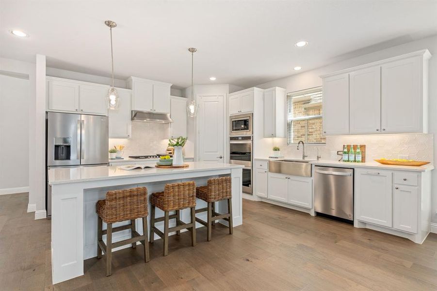 Kitchen featuring decorative light fixtures, double oven, gas cooktop, and apron sink