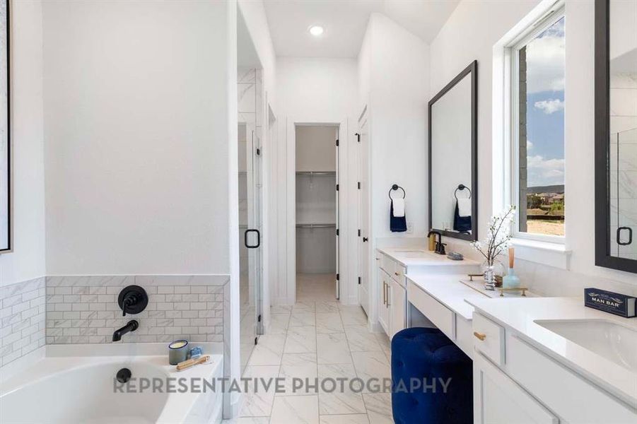 Bathroom featuring light marble finish flooring, double vanity, a bath, a spacious closet, and a shower stall