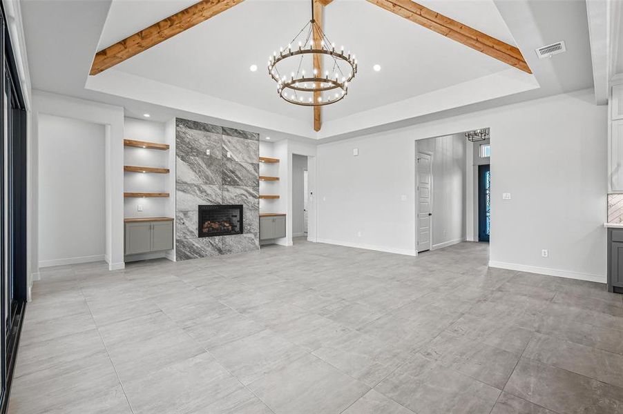 Unfurnished living room featuring beam ceiling, a high end fireplace, a chandelier, a raised ceiling, and recessed lighting Unfurnished living room featuring beam ceiling, a high end fireplace, a chandelier, a raised ceiling, and recessed lighting