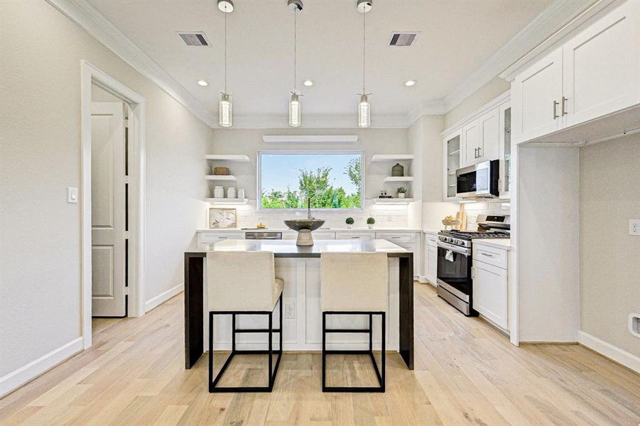 Bright kitchen with large island, featuring stainless steel appliances and quartz countertops.