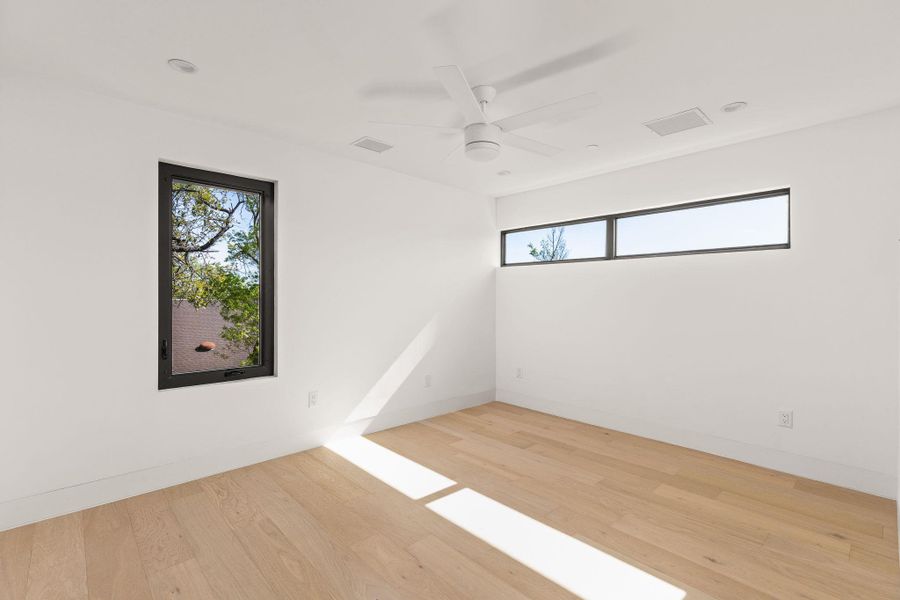 Empty room featuring light wood-type flooring, ceiling fan, and plenty of natural light