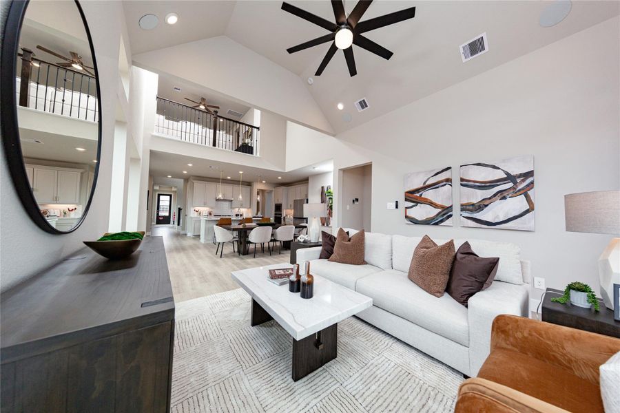This impressive view from the great room perfectly highlights the home's spectacular open-concept living space and soaring vaulted ceilings. The expansive main level flows effortlessly from the inviting family room into the central dining area and gourmet kitchen beyond, making it an entertainer's dream. Overhead, a dramatic loft looks down onto the living area, accentuating the architectural depth, incredible height, and connected layout of this multi-level floor plan.