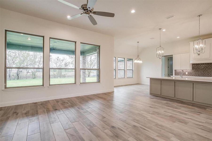 Kitchen with pendant lighting, ceiling fan, backsplash, white cabinetry, and light hardwood / wood-style flooring