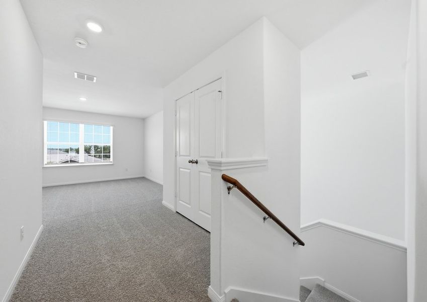 Second-floor game room viewed from the hallway, featuring the staircase and wood-look vinyl flooring. Second-floor game room viewed from the hallway, featuring the staircase and wood-look vinyl flooring.