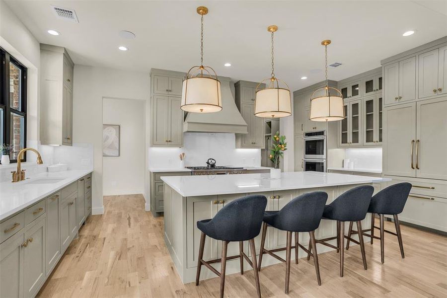 Kitchen with gray cabinets, a kitchen breakfast bar, pendant lighting, a spacious island, and recessed lighting Kitchen with gray cabinets, a kitchen breakfast bar, pendant lighting, a spacious island, and recessed lighting