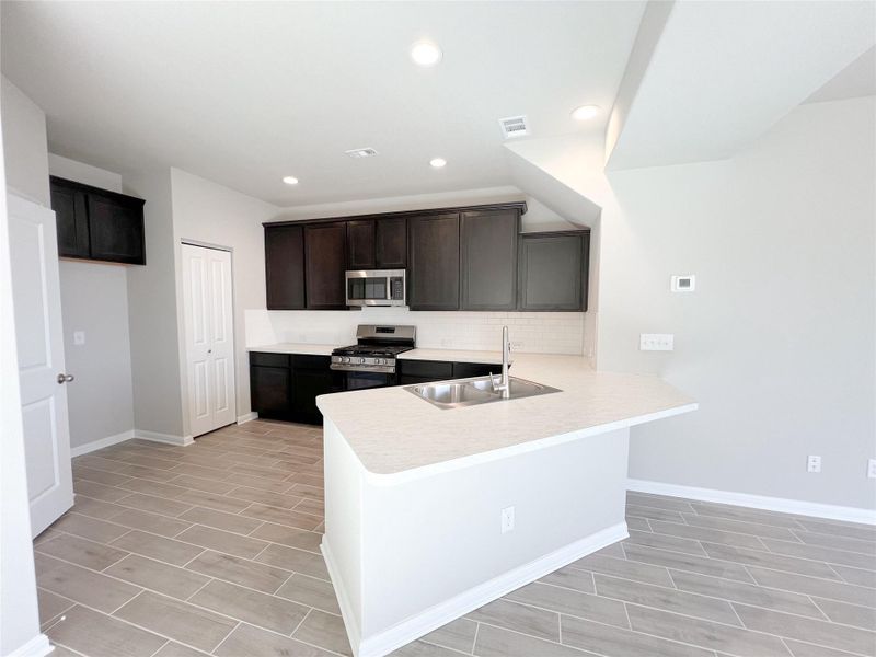 Kitchen with tasteful backsplash, a sink, visible vents, a peninsula, and appliances with stainless steel finishes Kitchen with tasteful backsplash, a sink, visible vents, a peninsula, and appliances with stainless steel finishes