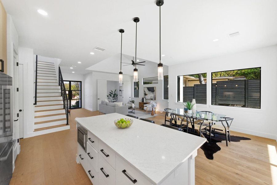Kitchen featuring a center island, white cabinetry decorative light fixtures, light wood-style flooring, and recessed lighting Kitchen featuring a center island, white cabinetry decorative light fixtures, light wood-style flooring, and recessed lighting