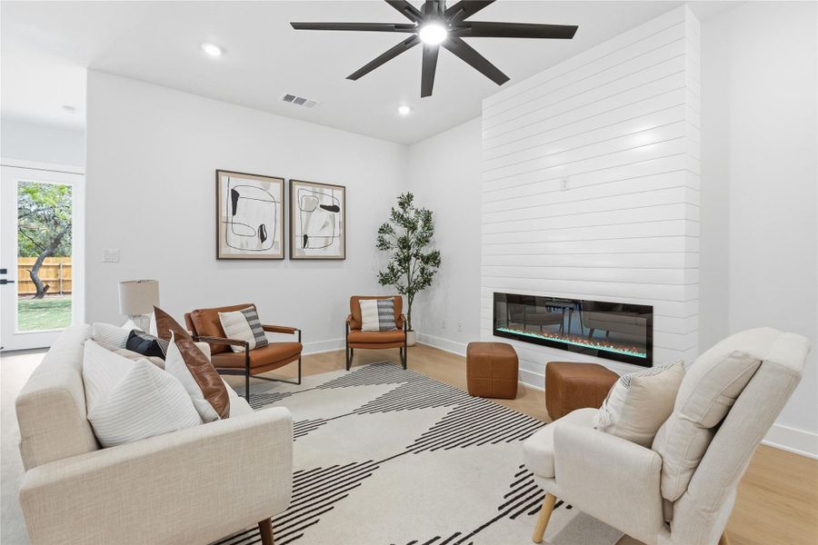 Living room with a fireplace, recessed lighting, a ceiling fan, and light wood-style flooring