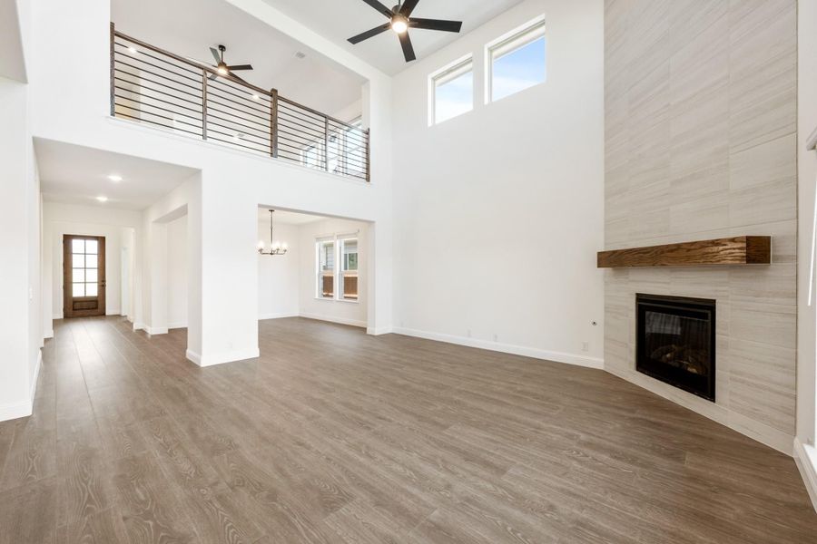 Open living room with two-story ceiling, fireplace, wood floors, and second-floor railing overlook