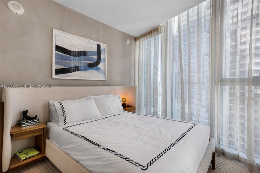 Full-height floor-to-ceiling windows with integrated drapery track, neutral textured wall finish, and wall-to-wall carpeting