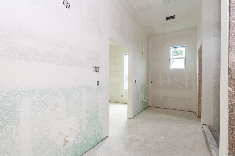Spacious unfinished primary bathroom with high ceilings and ample natural light from two windows, offering a blank canvas for customization. Spacious unfinished primary bathroom with high ceilings and ample natural light from two windows, offering a blank canvas for customization.