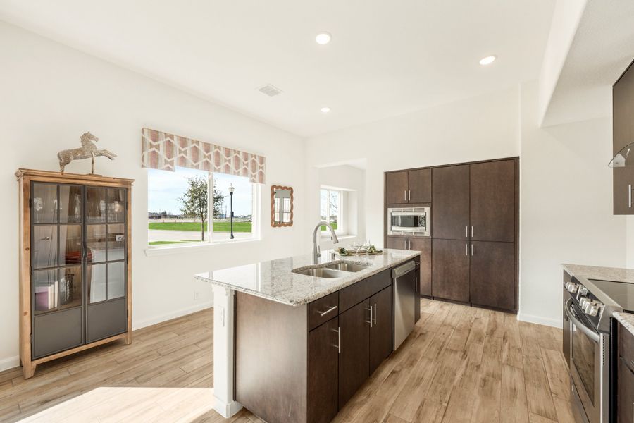 Kitchen with center island, granite countertops, dark wood cabinets, and light hardwood floors