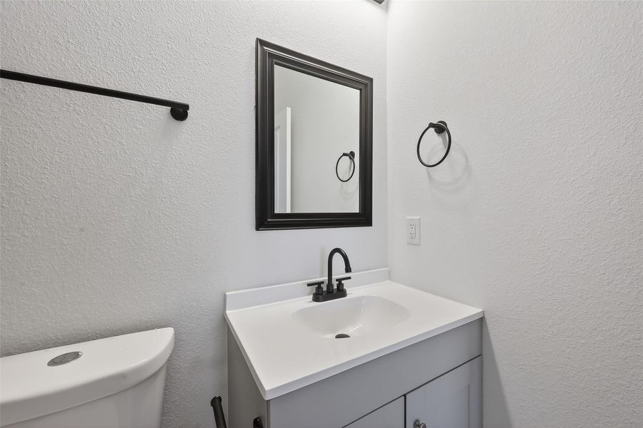 This bathroom features a modern design with a sleek white vanity, black fixtures, and a wall-mounted mirror framed in black. It has a simple, clean aesthetic perfect for contemporary tastes.