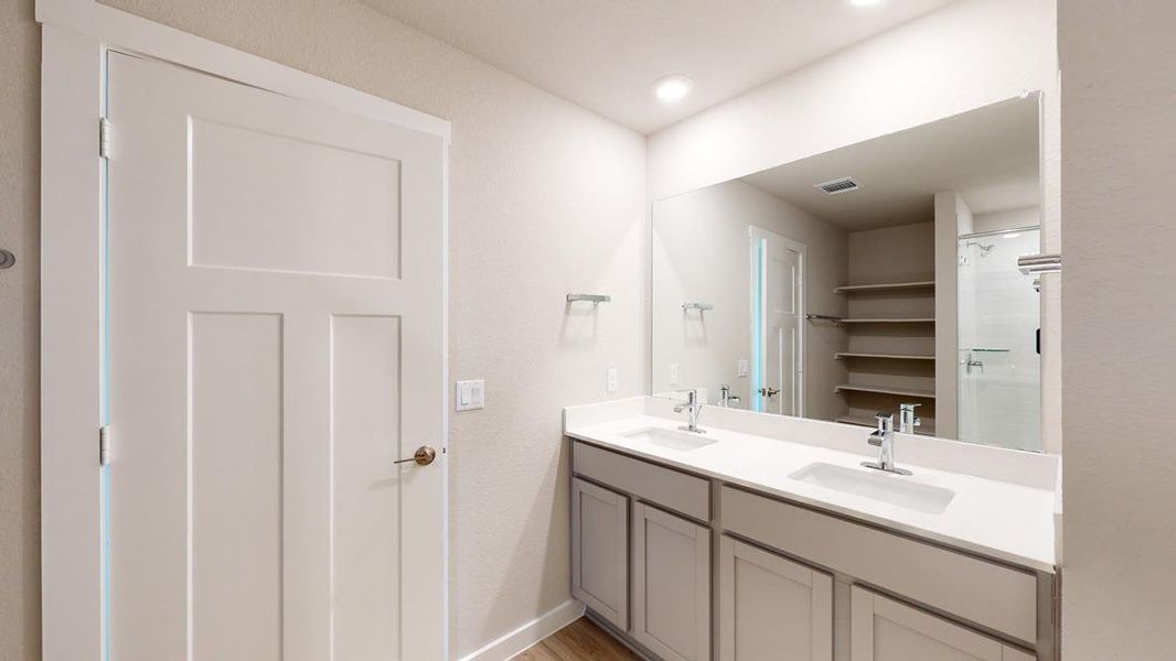 Bathroom with double vanity, a shower stall, and light wood-type flooring