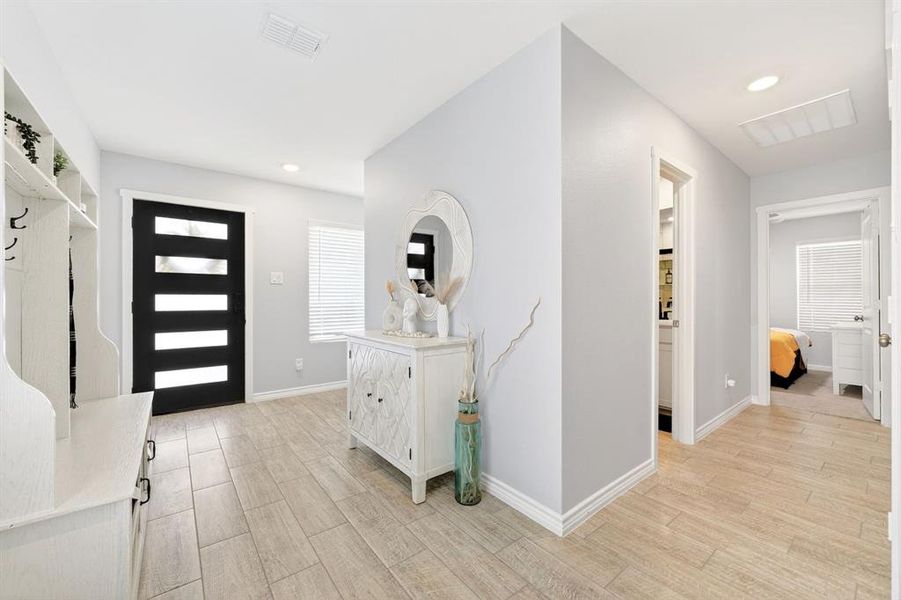 Entryway featuring wood-finish tile flooring, a contemporary black entry door with frosted glass panels, and recessed lighting