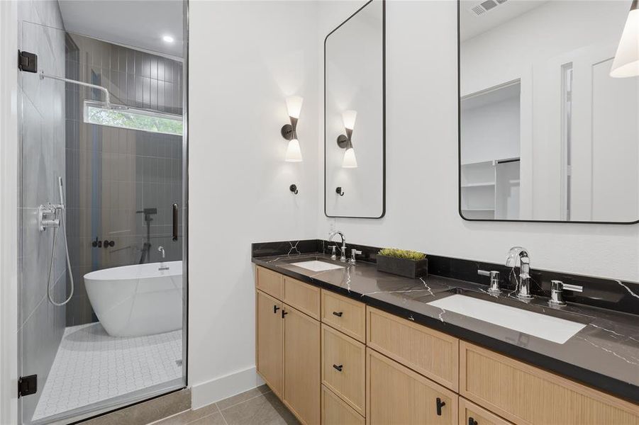 Dual vanity featuring a dark countertop with white veining, undermount sinks, and light wood-finish cabinetry Dual vanity featuring a dark countertop with white veining, undermount sinks, and light wood-finish cabinetry