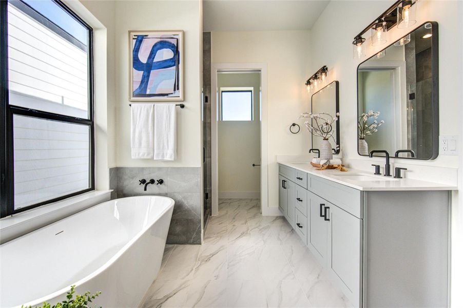 Luxurious primary bathroom featuring a sleek soaking tub, dual vanities with elegant fixtures, and abundant natural light.