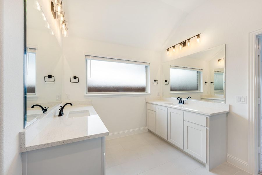 Bathroom with dual vanities, white quartz countertops, black fixtures, and large mirrors with overhead lighting Bathroom with dual vanities, white quartz countertops, black fixtures, and large mirrors with overhead lighting