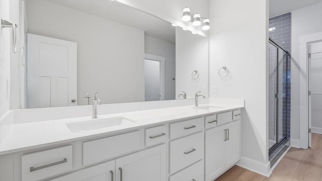 Exceptional en-suite with dual vanity and glass-enclosed tiled  walk-in shower for superior everyday comfort