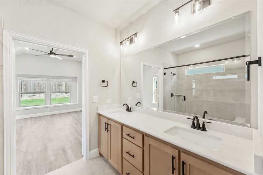 Ensuite bathroom with double vanity, wood cabinets, white countertops, and glass walk-in shower