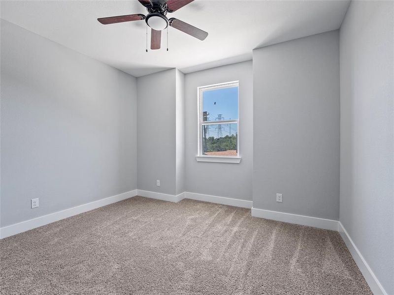 Carpeted spare room featuring ceiling fan and baseboards