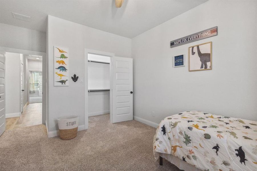 Carpeted bedroom featuring a spacious closet, ceiling fan, and a closet