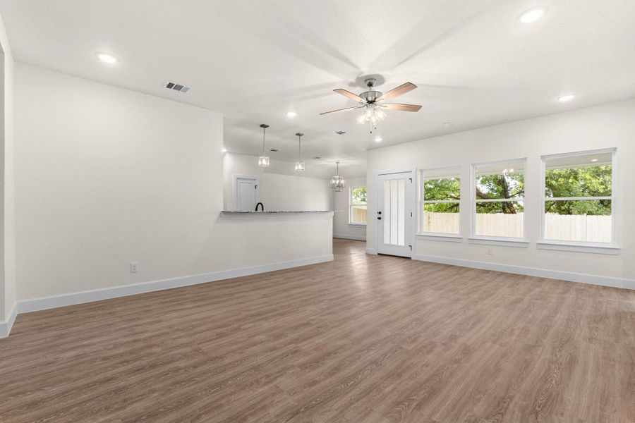 Unfurnished living room featuring light wood finished floors, recessed lighting, a ceiling fan, and a chandelier