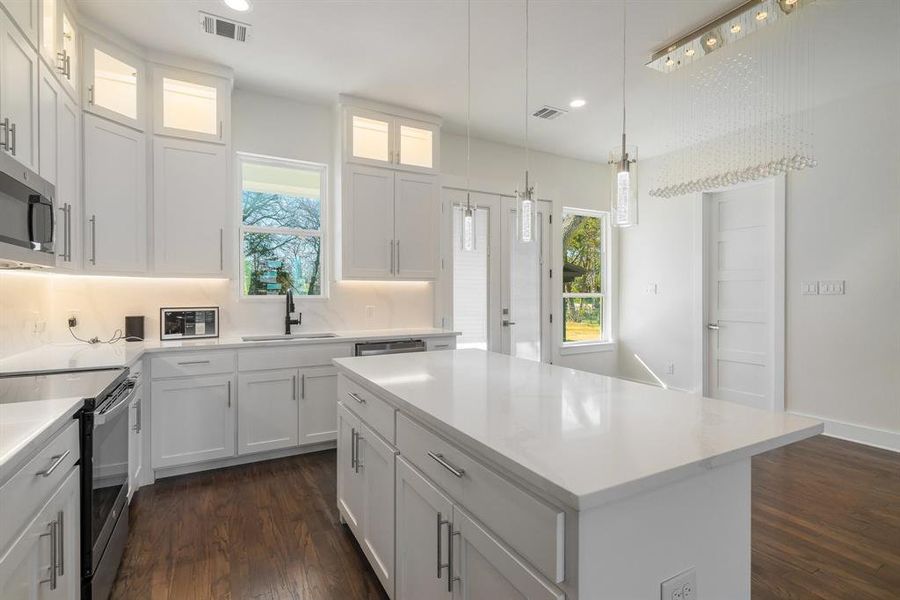 Kitchen featuring stainless steel appliances, dark hardwood / wood-style flooring, pendant lighting, white cabinets, and a center island