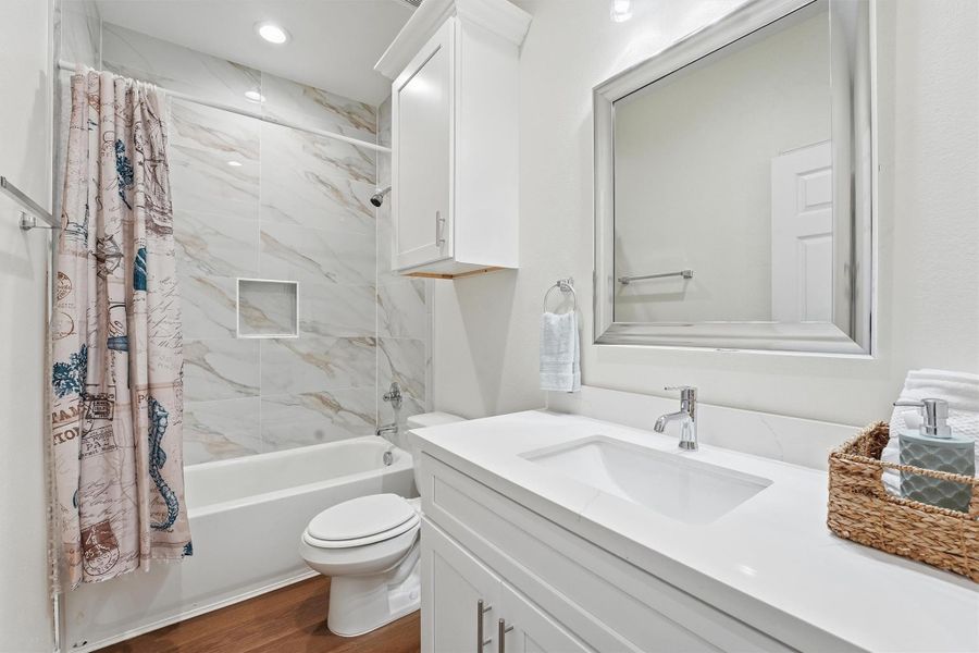 The second bathroom features modern finishes and tile surrounds, offering a polished look that complements the home’s new-construction quality.