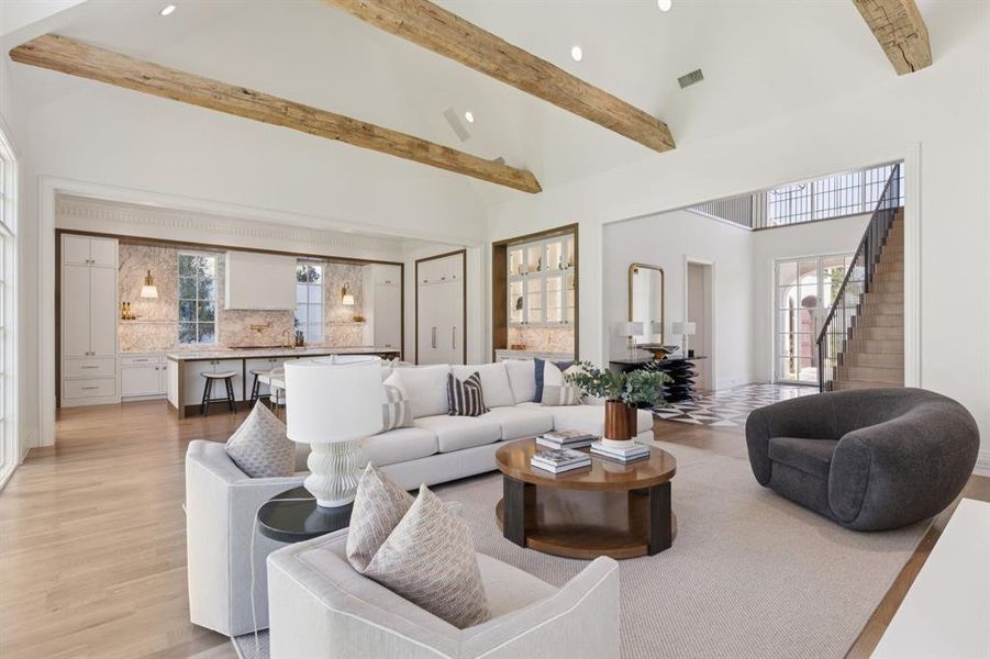 Living area featuring high vaulted ceiling, recessed lighting, beam ceiling, light wood finished floors, and stairs