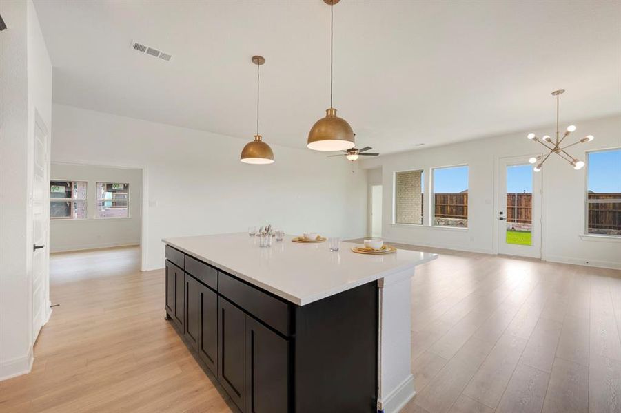 Kitchen with open floor plan, dark cabinets, light wood-style floors, and a kitchen island Kitchen with open floor plan, dark cabinets, light wood-style floors, and a kitchen island