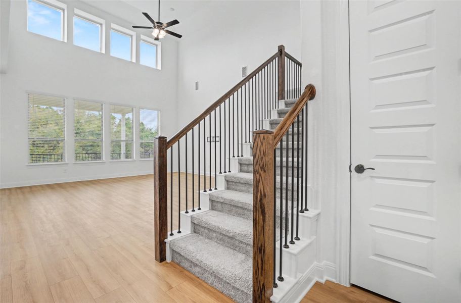 Staircase featuring wood finished floors, a high ceiling, and ceiling fan