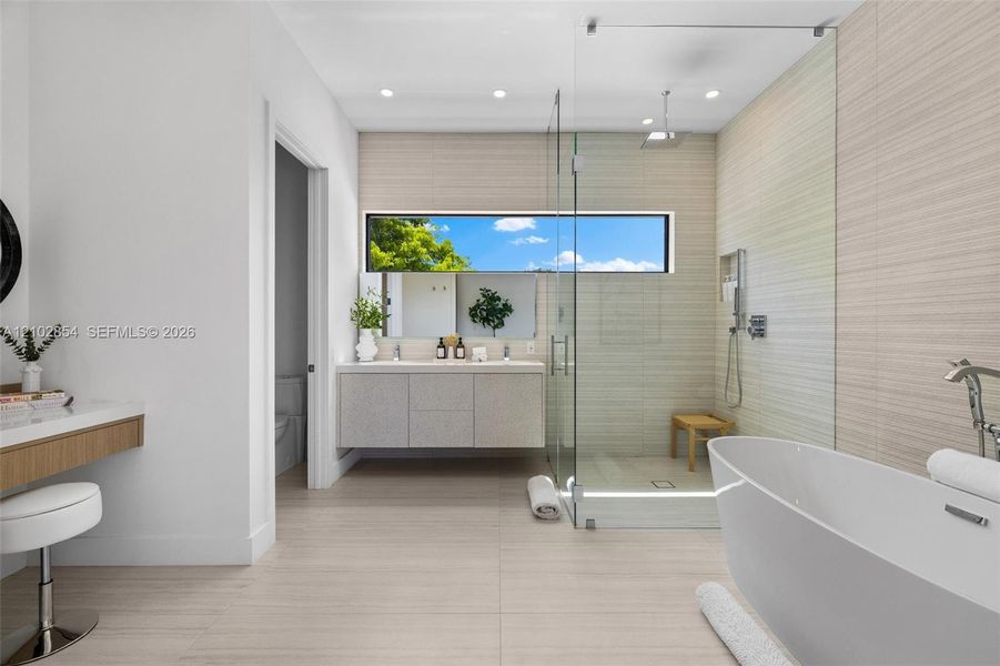 Floating vanity with integrated dual sinks, freestanding soaking tub, walk-in glass-enclosed shower, horizontal ribbon window, and floor-to-ceiling tile work